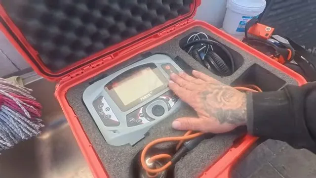 Acoustic leak detector with headphones open in a red carry case under a hand