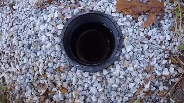 Black cleanout pipe standing in a bed of grey gravel