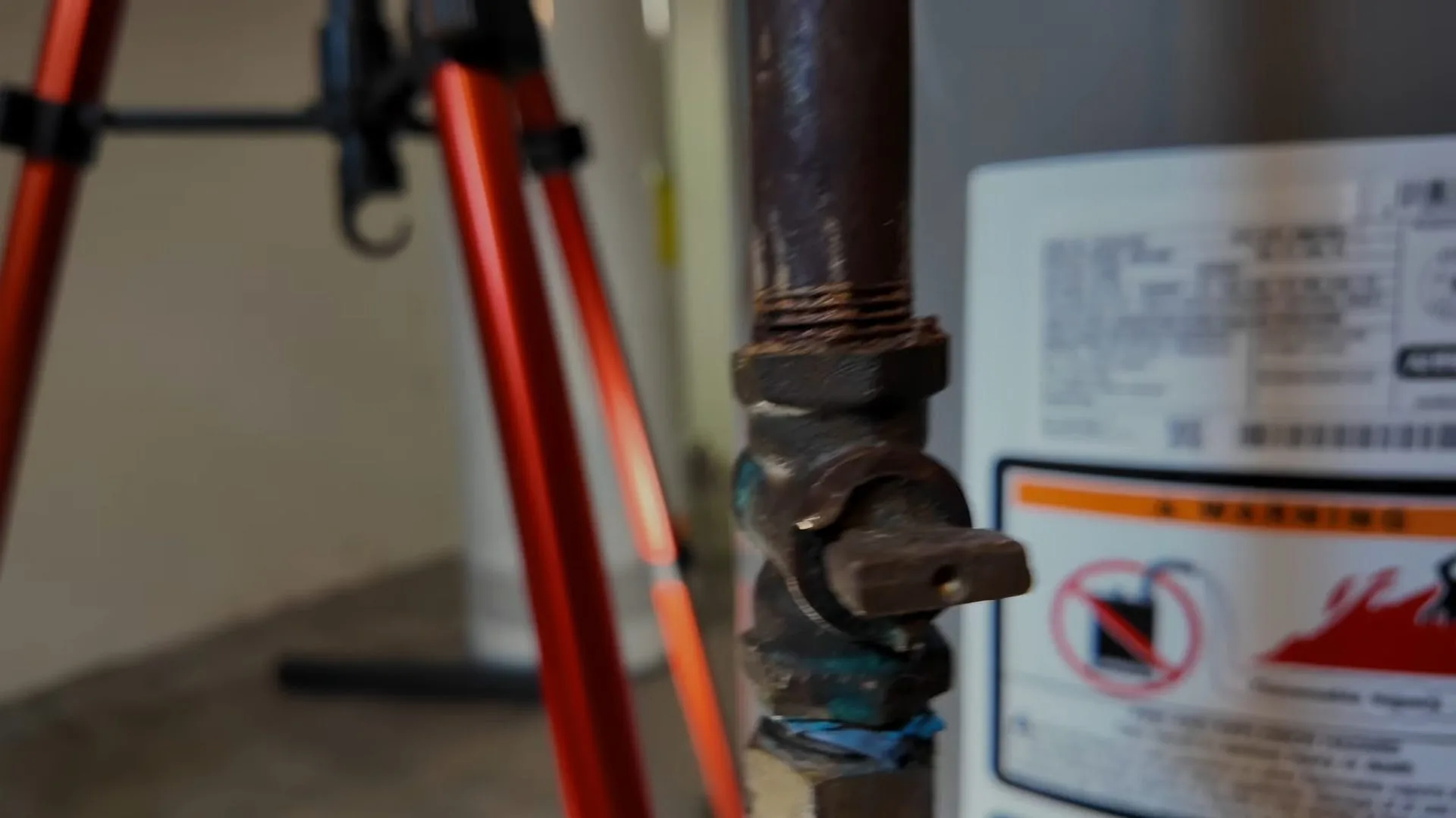 Black iron gas valve beside an appliance with a warning label on it
