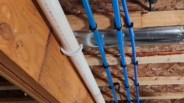Blue PEX supply lines clipped along floor joists beside a white drain pipe