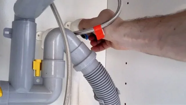 Hand attaching a braided supply hose beside the trap under a basin