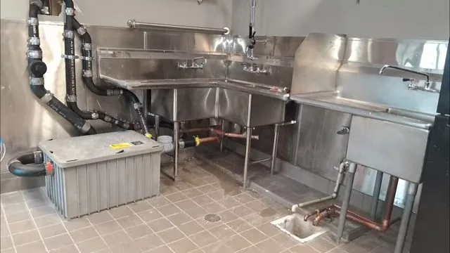 Stainless steel commercial kitchen with prep sinks, a grey grease interceptor and a floor drain