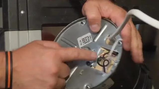 Hands working on the underside plate of a garbage disposal with a white hex key