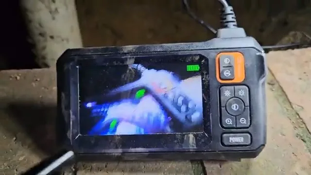 Handheld inspection monitor lying on the ground showing the inside of a pipe