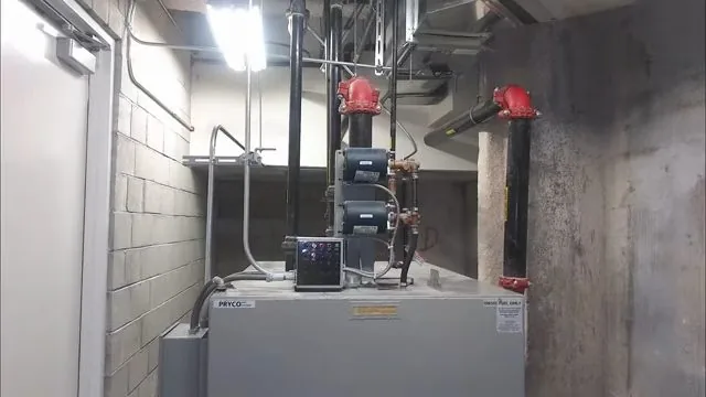 Small mechanical room with grey pumps, red valves and black steel pipework