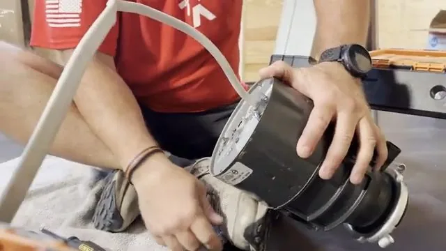 Person holding a replacement garbage disposal up towards a sink mount