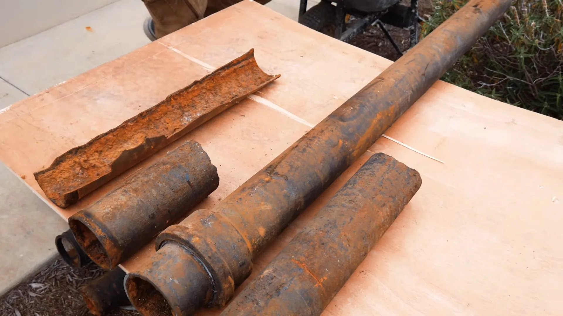 Sections of rusted cast iron pipe cut out and laid on a board