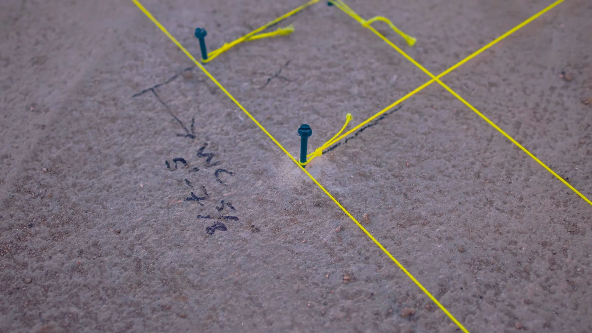 Slab floor marked with yellow string lines, pins and handwritten notes
