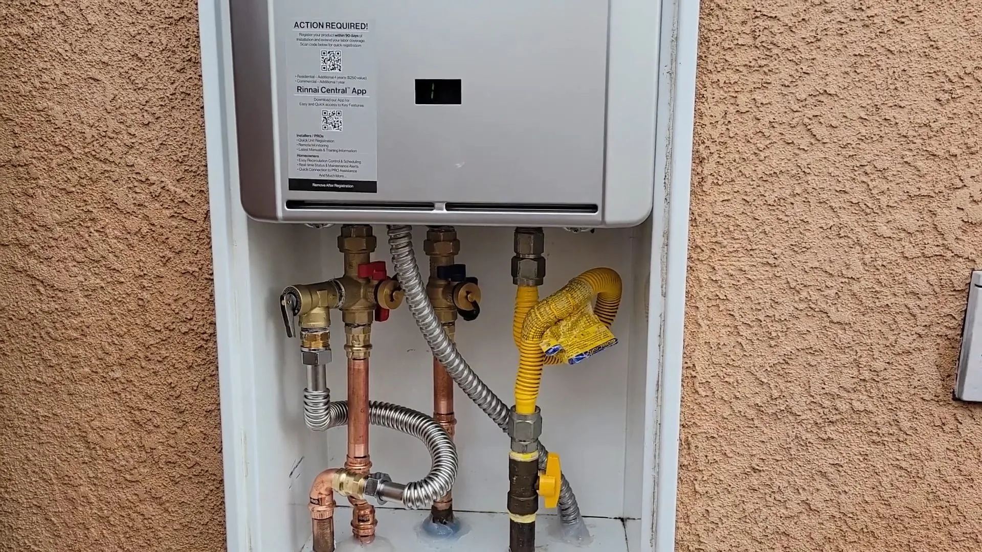 Wall-mounted tankless water heater in a recessed box with gas and water connections below